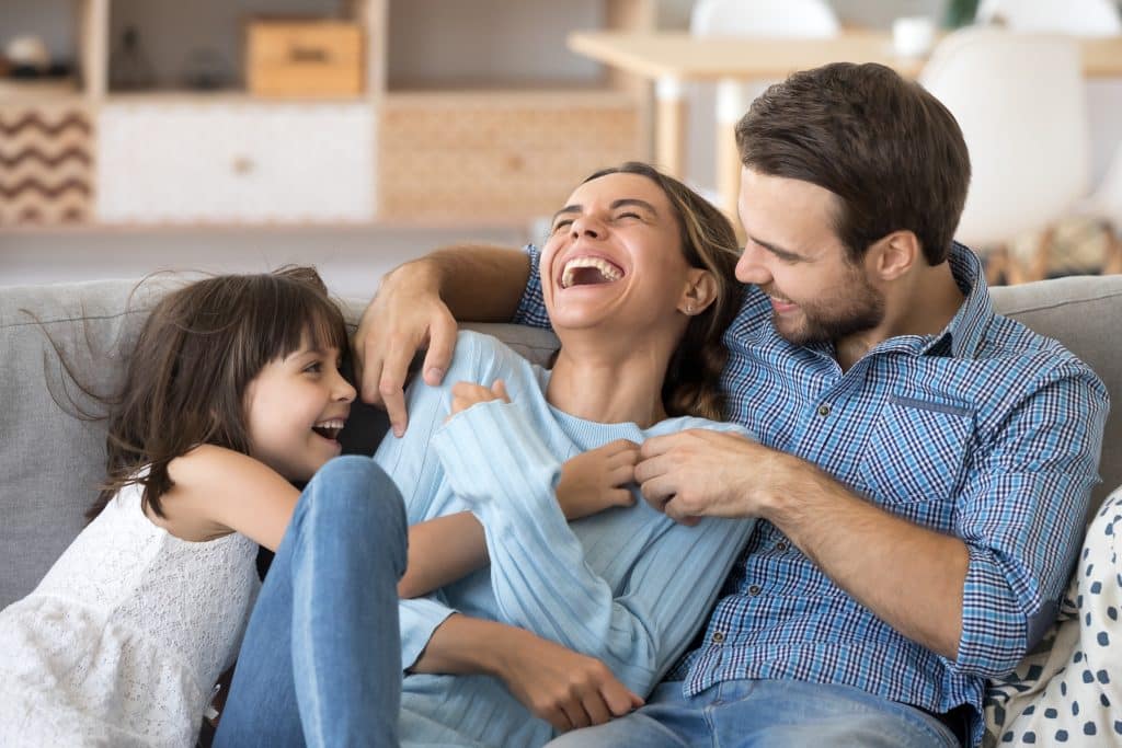 Photo d'une enfant et ses parents qui rigolent ensemble